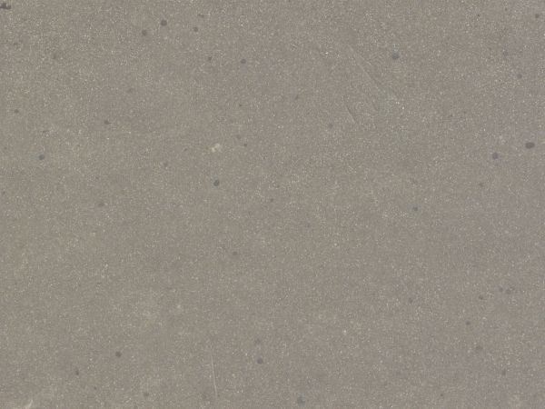 Asphalt texture with tiny bits of white rock embedded in its rough tan surface.